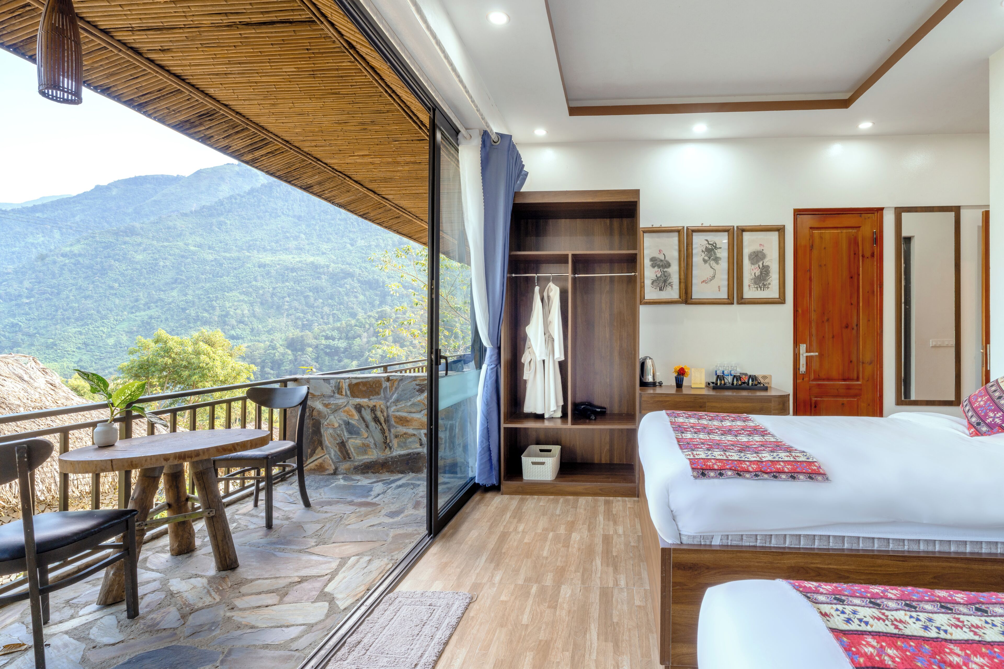 A hotel room with a balcony, a bed, a wardrobe, and a table with chairs.
