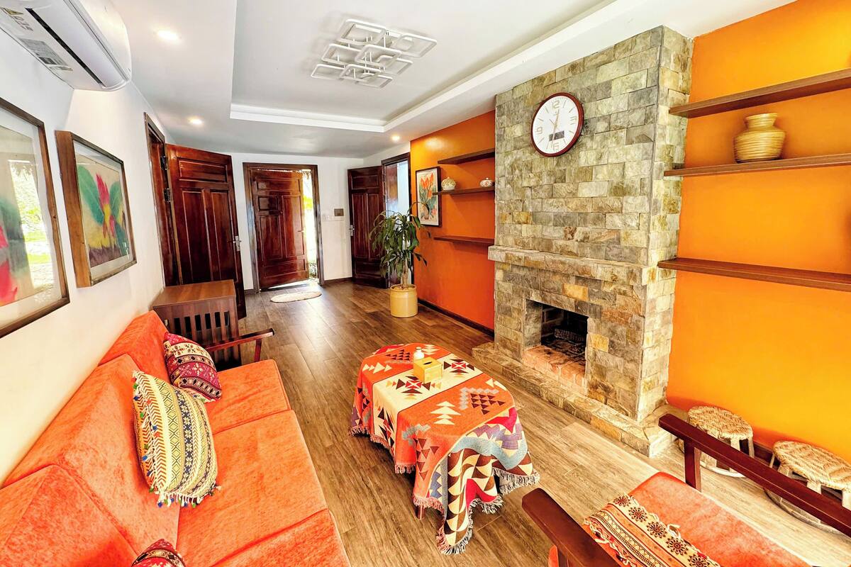 A hotel lobby with a wooden floor, orange walls, a stone fireplace, and a clock.