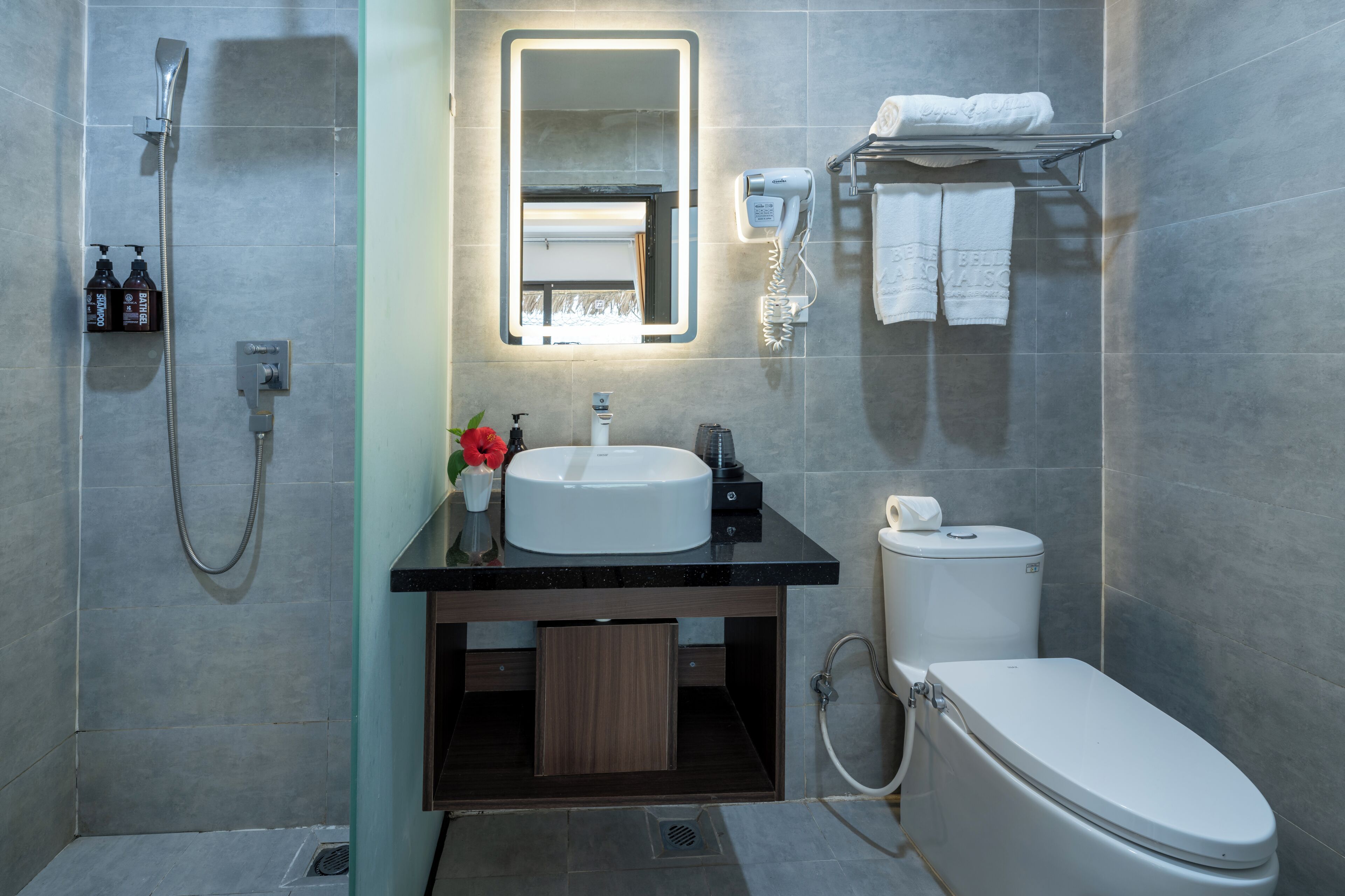 A modern bathroom with a shower, sink, toilet, and a mirror with built-in lighting.