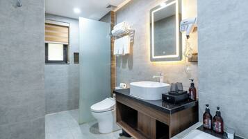 A modern bathroom with a toilet, sink, and bathtub. There is a mirror above the sink and a towel rack with towels.