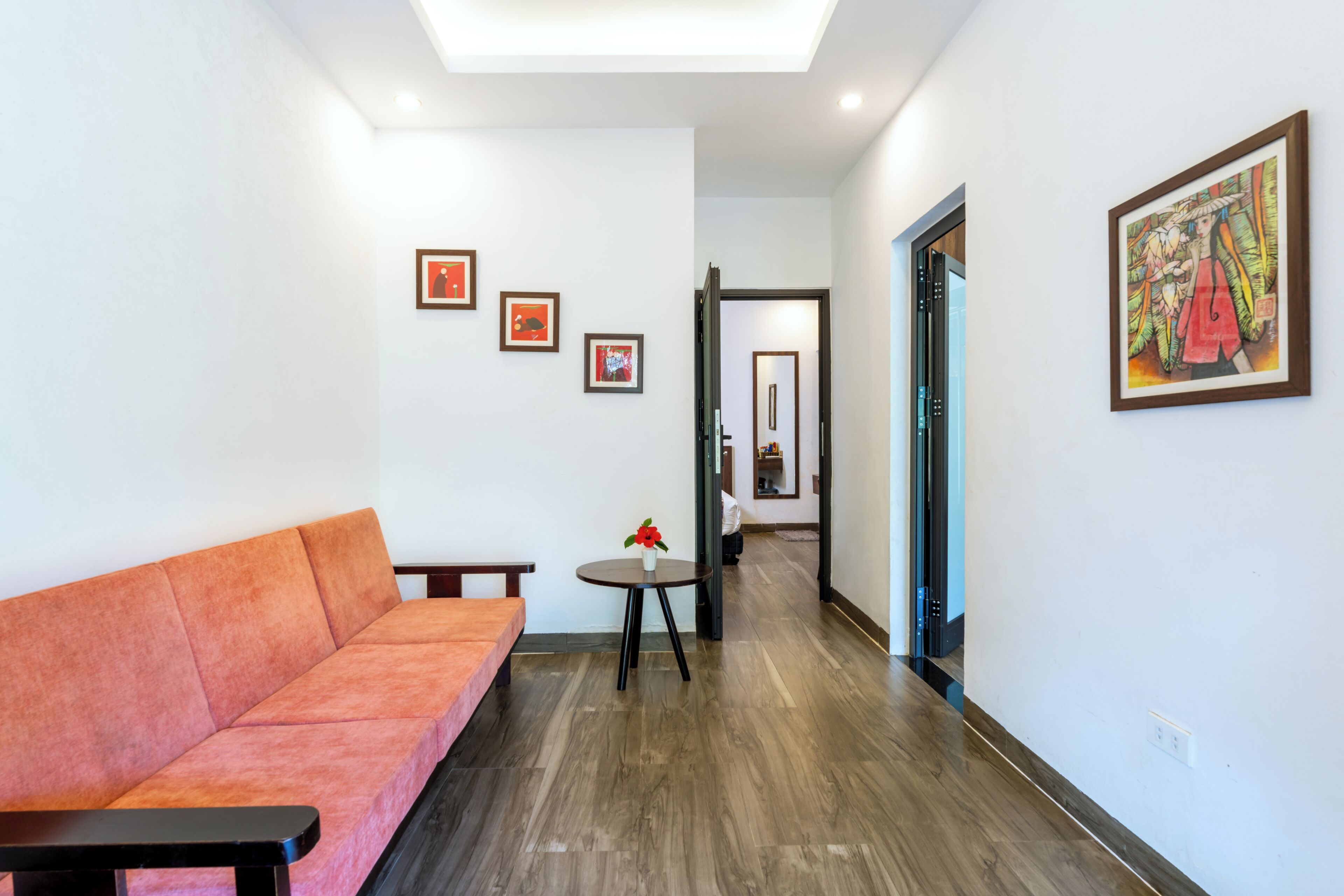 A modern interior with a sofa, a small table with a vase, and framed artwork on the walls.