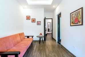 Un interior moderno con un sofá, una mesita con un florero y obras de arte enmarcadas en las paredes.