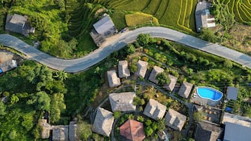 A residential area with a winding road, houses with thatched roofs, and a swimming pool.