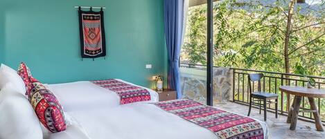 A bedroom with a bed, a nightstand, a window with curtains, and a balcony with a table and chair.