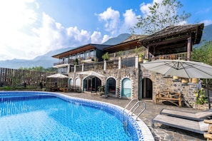 A hotel with a swimming pool, stone facade, and mountain views. - Belle Maison Sapa Resort & Spa - Formerly Sapa Eco Villas & Spa (Ta Van)