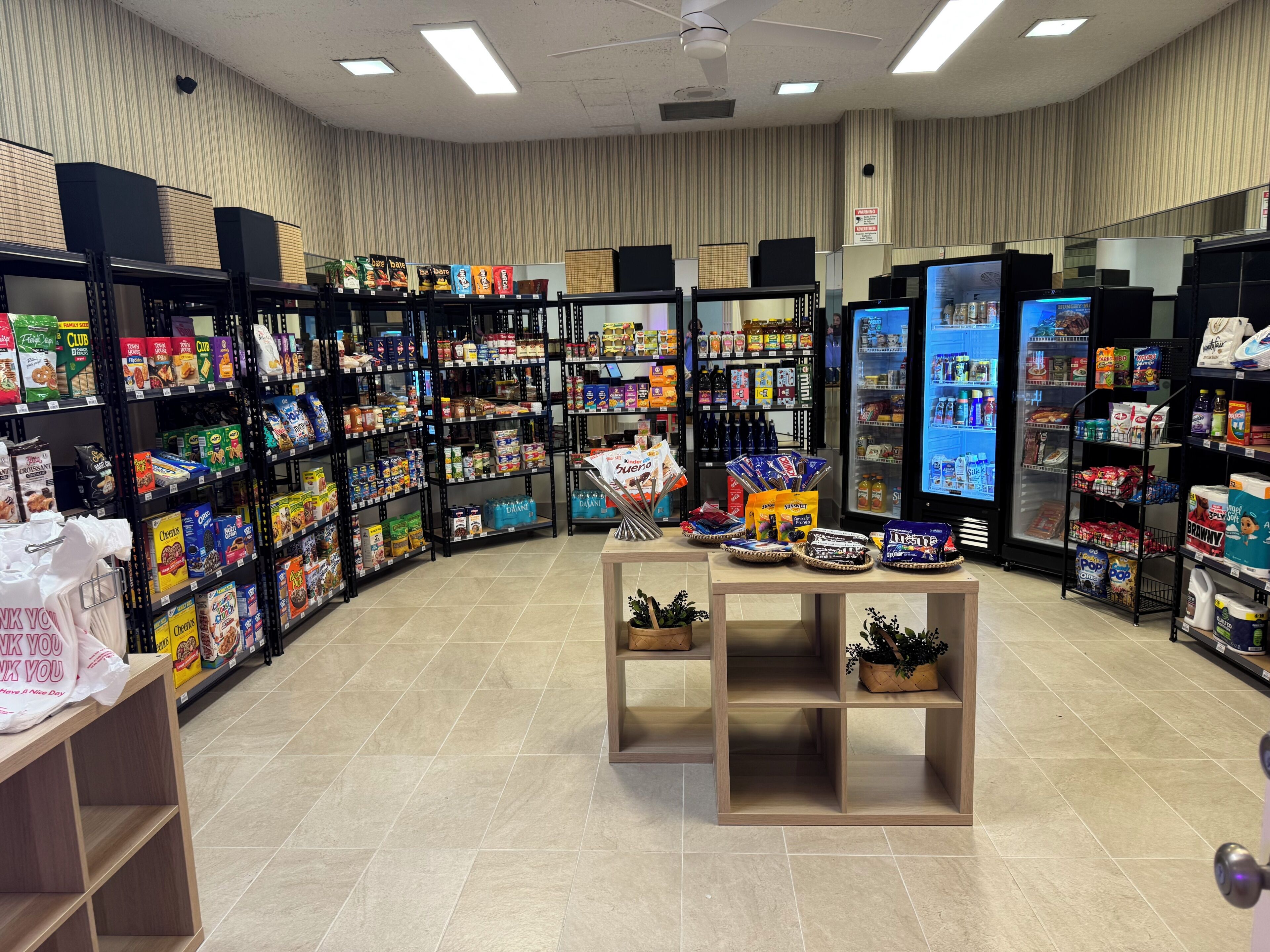 Een supermarkt met schappen vol diverse producten, een koelvitrine en een kassabalie.