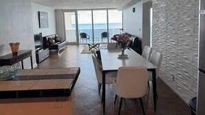 Un salon moderne comprenant un coin repas, un canapé, un téléviseur et une vue sur la mer.