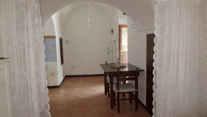 Un espace repas comprenant une table et des chaises, un sol carrelé et des murs blancs.