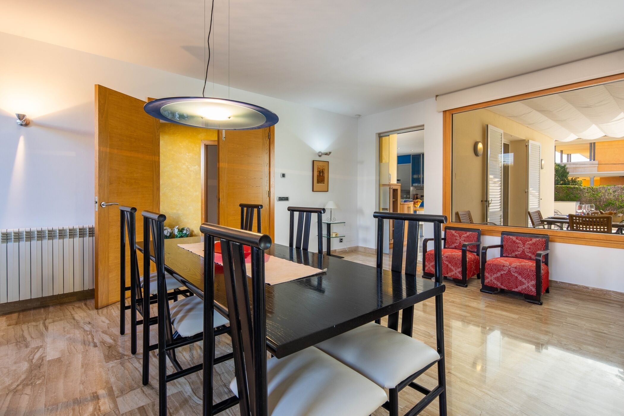 A dining area with a black table and chairs, a wooden door, and a large mirror reflecting the room.