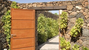 A wooden gate leading to a stone pathway surrounded by lush greenery. - Magnificent and spacious Pearl Villa with heated pool, Wifi and AC (puerto del carmen)