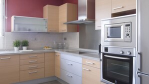A modern kitchen with wooden cabinets, a built-in microwave, and an oven. - Magnificent and spacious Pearl Villa with heated pool, Wifi and AC (puerto del carmen)