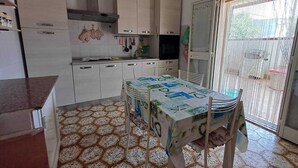 Eine Küche mit Esstisch, Schränken und Fliesenboden.
