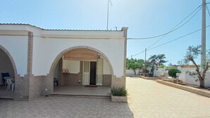 Ein Wohngebäude mit einer gefliesten Terrasse, einem Rundbogenportal und einer sichtbaren Satellitenschüssel.