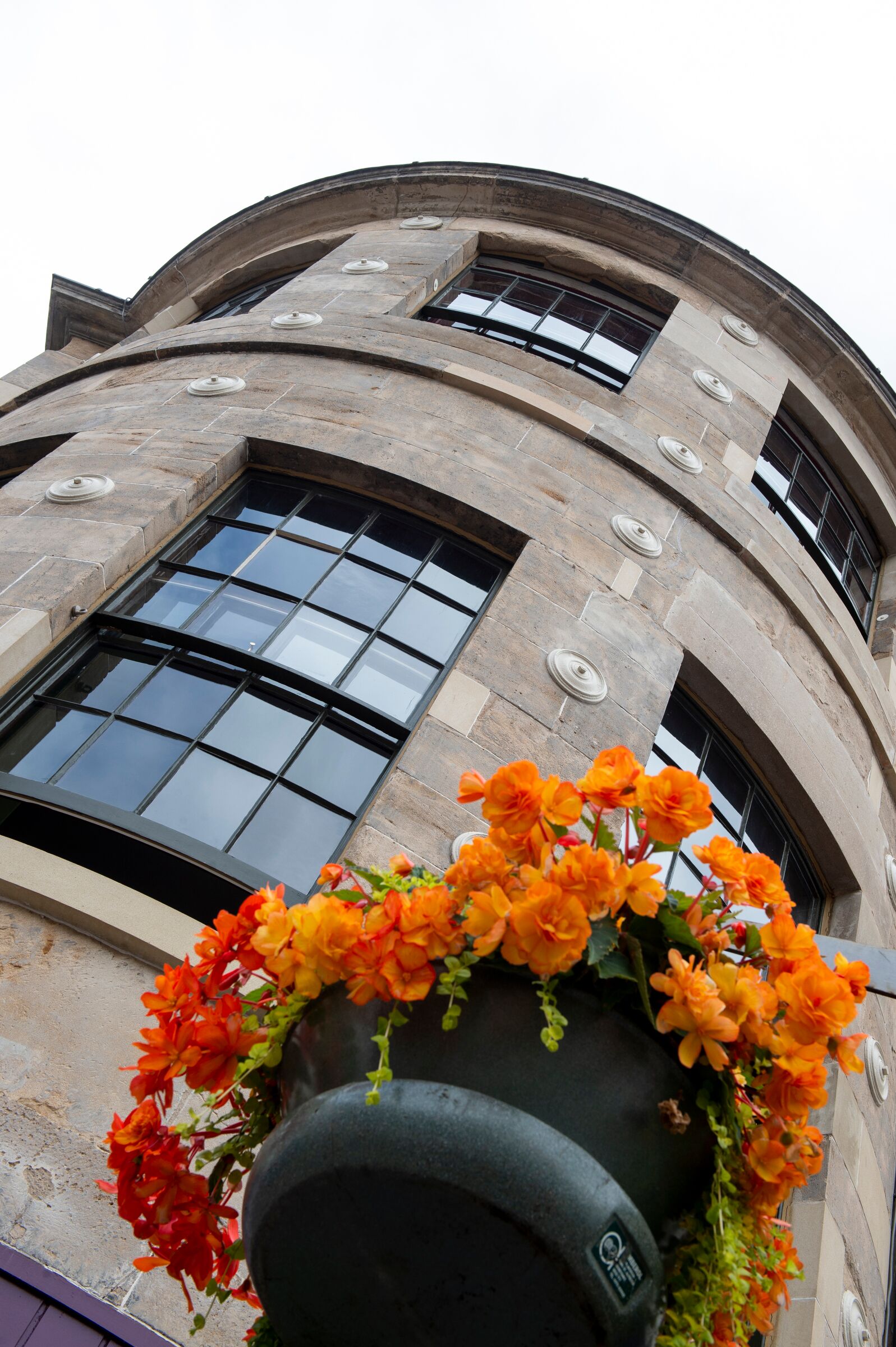 A building with a curved facade, large windows, and a flower planter in the foreground.