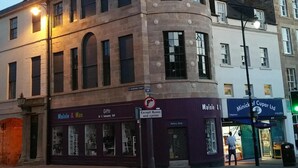 A historic building with a clock tower, a shop named Maisie & Mae, and a gallery shop. - Unique Historic Apartment sleeping 7 close to St Andrews (Cupar)