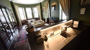 A modern kitchen with a built-in oven, a sink, and a coffee maker. There is a dining area with a table and chairs, and a large window with curtains. - Unique Historic Apartment sleeping 7 close to St Andrews (Cupar)