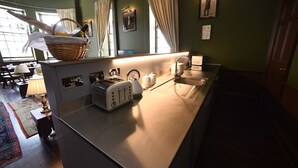 A kitchen with a toaster, a sink, and a basket containing bread and a bottle. - Unique Historic Apartment sleeping 7 close to St Andrews (Cupar)
