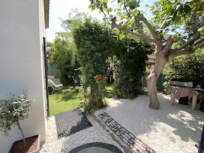 Un jardin avec une terrasse, un arbre et un banc.