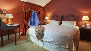 Un dormitorio con una cama grande, dos mesitas de noche con lámparas, una ventana con cortinas y un escritorio con lámpara.