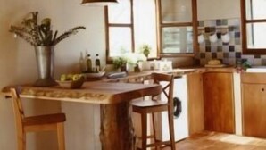 Una cocina rústica con vigas de madera, una isla grande con taburetes y un salpicadero de azulejos.