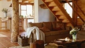 Un interior rústico con vigas de madera a la vista, un sofá, una mesita de centro y un comedor.