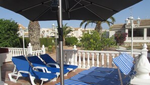 A terrace with sun loungers, a metal umbrella, and a white balustrade. - Beautiful villa with large outdoor kitchen for max. 10 people, swimming pool, air conditioning and wifi (Cdad. Quesada)