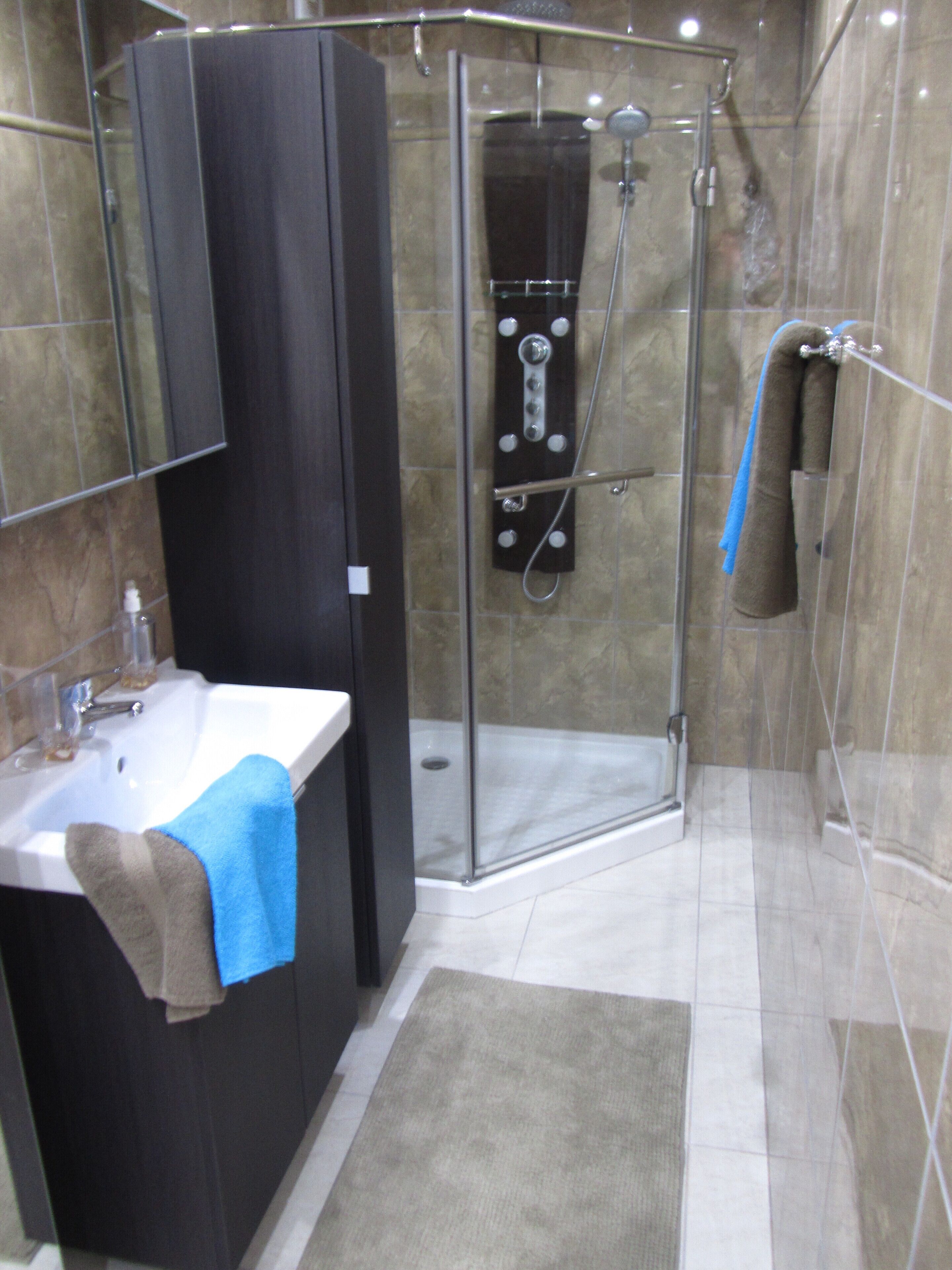 A modern bathroom with a glass-enclosed shower, a sink with a towel, and a mirror above the sink.