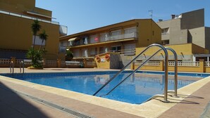 Ein Schwimmbecken mit Metallleitern, umgeben von einer gefliesten Terrasse.