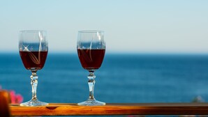 Twee wijnglazen op een houten oppervlak met uitzicht op de oceaan.