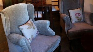 A room with two grey armchairs, a dining table with chairs, a large wall painting, and a hanging light fixture. - Casiopea charming lodging for two persons (Braojos)