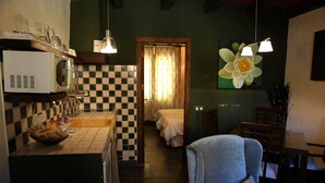 A compact kitchen with a microwave, sink, and a bowl of snacks. A chair with a floral pillow is in the foreground. - Casiopea charming lodging for two persons (Braojos)