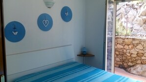 A bedroom with a bed, a nightstand, and a wall with three circular decorations. - VILLA Belvedere AZZURRA (Costa Paradiso)