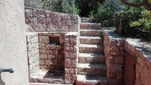 A stone staircase leading to a small opening in a wall, surrounded by greenery. - VILLA Belvedere AZZURRA (Costa Paradiso)
