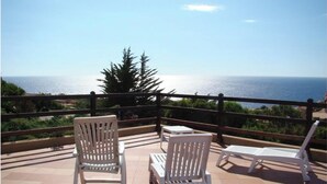 A terrace with white chairs and a table, overlooking a body of water and greenery. - VILLA Belvedere AZZURRA (Costa Paradiso)