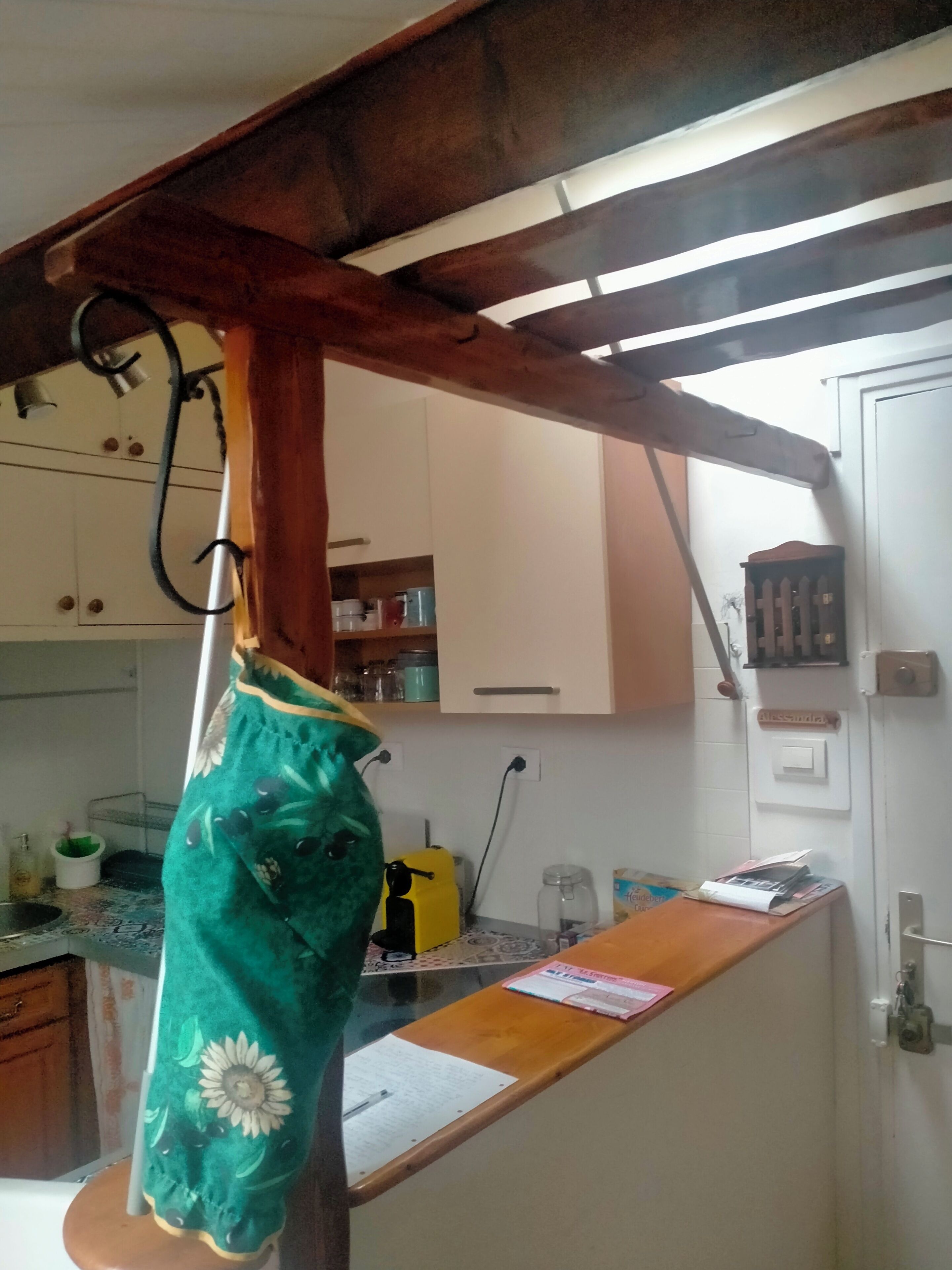 A kitchen with wooden beams, a countertop, and various kitchen appliances.