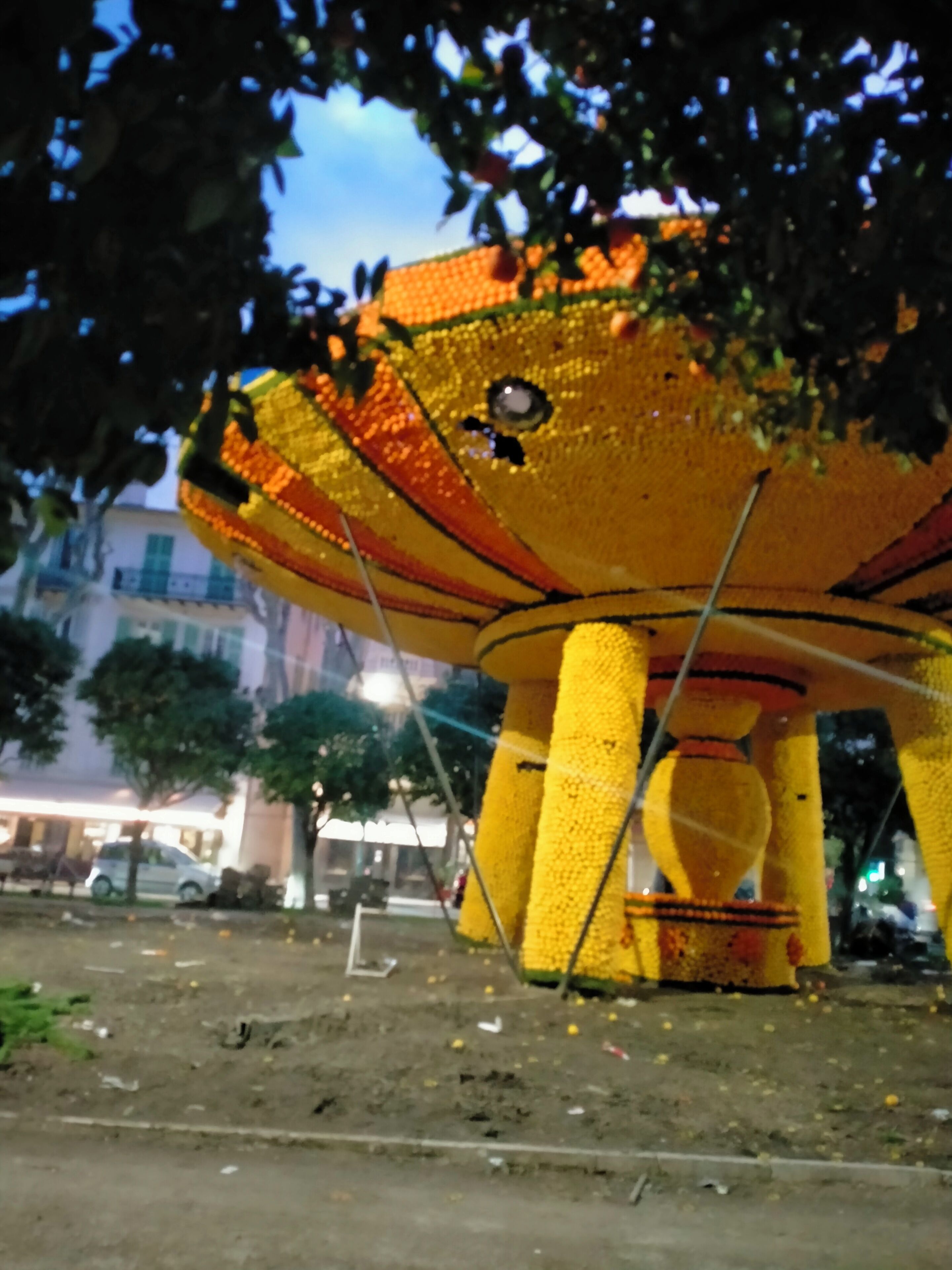 A large, yellow, flower-shaped structure in an outdoor setting.