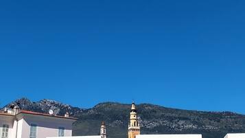 A building with a flat roof and a bell tower, set against a mountainous backdrop.