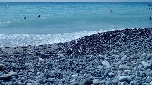 Una playa con costa rocosa y cielo azul despejado.
