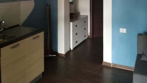 A kitchen with a wooden countertop, a sink, and a cabinet. There is a hallway with a blue wall and an archway leading to another room. - Cottage in the countryside 400 m from the sea (Parghelia)