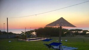 A grassy area with lounge chairs and a thatched umbrella, likely a relaxation zone. - Cottage in the countryside 400 m from the sea (Parghelia)