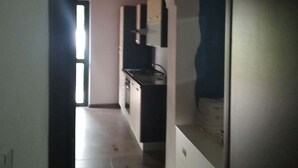 A narrow hallway leading to a kitchen with a white cabinet and a black countertop. - Cottage in the countryside 400 m from the sea (Parghelia)