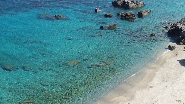 A beach with clear turquoise water, visible rocks, and a sandy shore. - Cottage in the countryside 400 m from the sea (Parghelia)