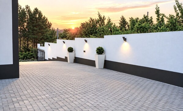 A modern outdoor area with a paved walkway, white walls, and planters with greenery. - Casa da Lameira - Castelo do Bode (Tomar)