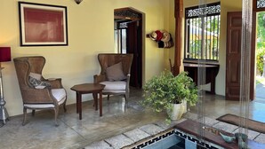 A cozy indoor area with wicker chairs, a small table, and a potted plant. - Premium Colonial Villa with Pool, charming Staff + Beach House (Ambalangoda)