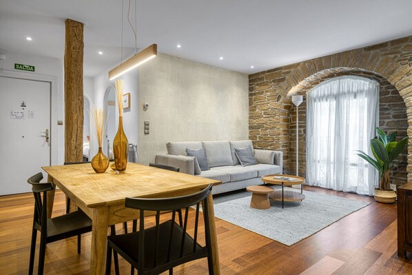 A modern living room with a stone wall, a wooden dining table, and a sofa.