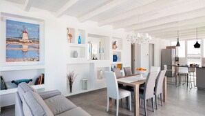 A modern living room with a dining area, white walls, and a large painting of a lighthouse. - Villa with private pool, 300 metres from beach - DiCasaInSicilia (Marsala)