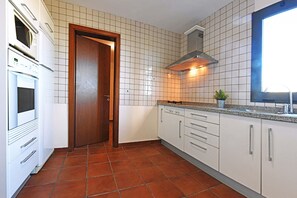 Eine Küche mit weißen Schränken, einer Holztür und einer gefliesten Spritzschutzwand.