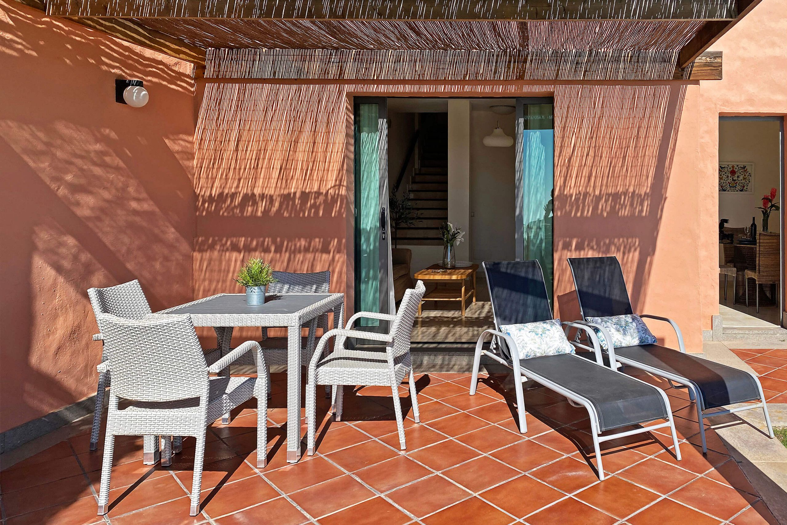 An outdoor patio with wicker furniture, a table, and a chair.