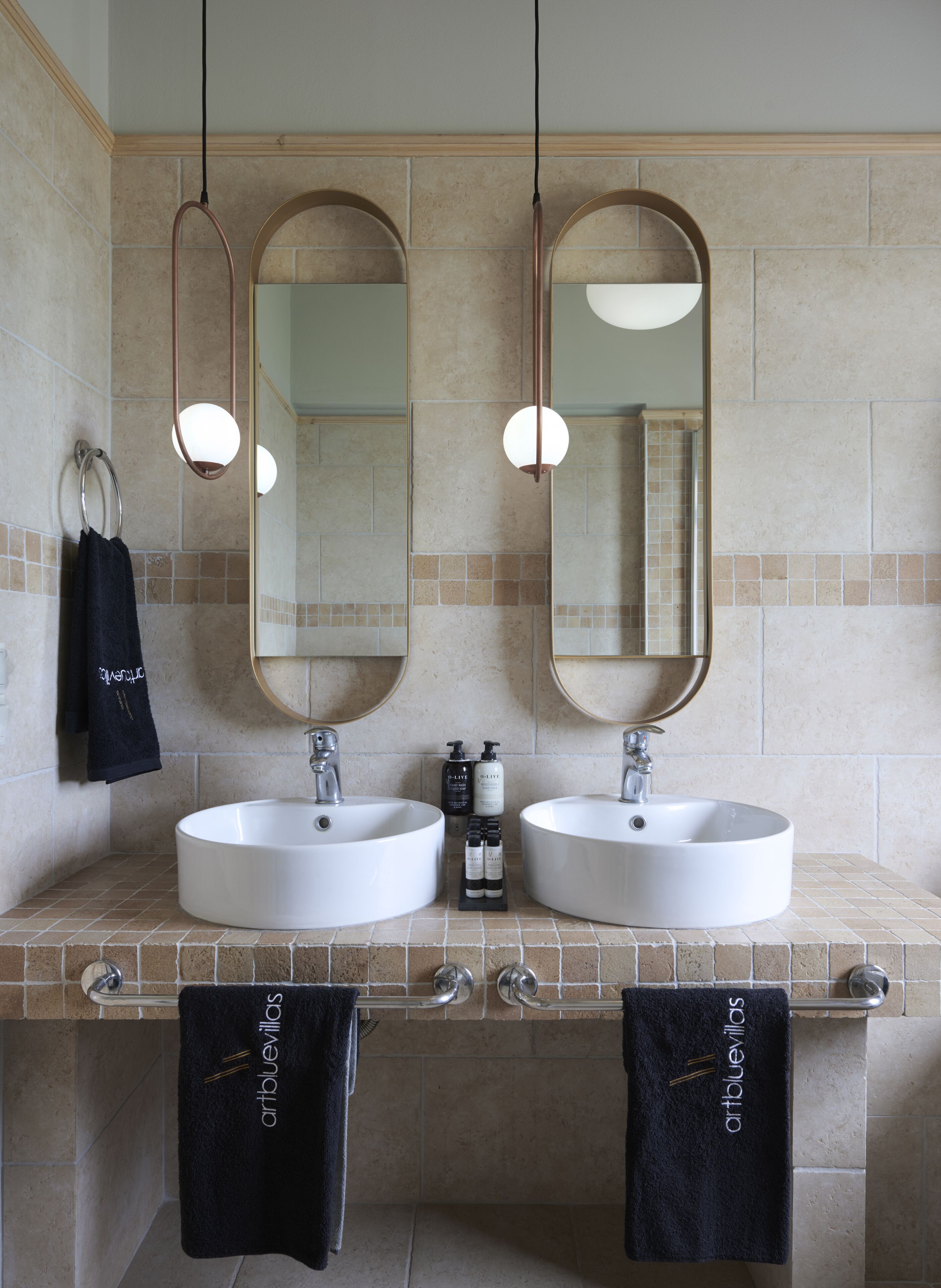 A bathroom with two sinks, two mirrors, and two towels hanging on towel racks.