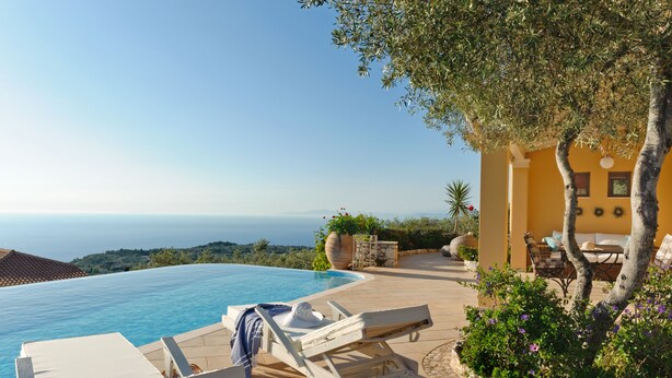 Zona de piscina con sillones de descanso, una planta en maceta y vistas al mar.